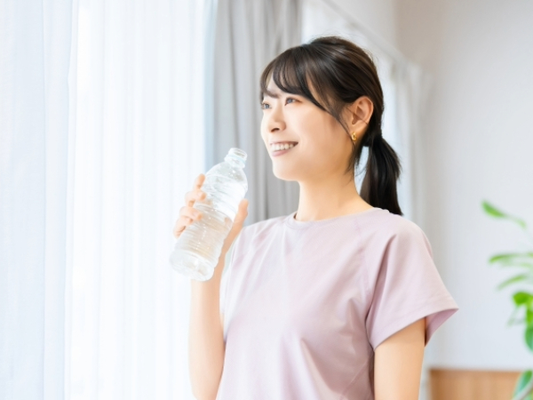 ペットボトルの水を飲む女性の画像