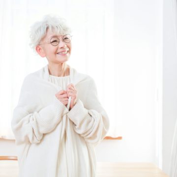 窓辺でほほ笑むシニア女性のイメージ画像